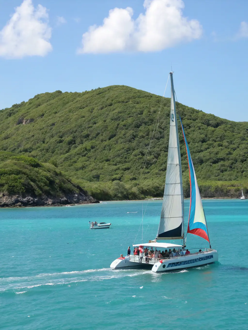A sleek and modern catamaran sailing through crystal-clear turquoise waters, highlighting the stability and speed of The Happy Captain's catamaran charters.